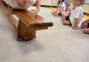 Dziewczynka przeciąga się na ławeczce.