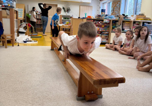 Chłopiec przeciąga się po ławeczce.