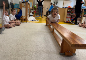 Dziewczynka przeciąga się po ławeczce.