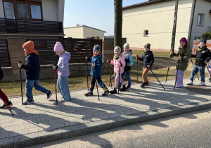 Zadowolone dzieci spacerują z kijkami.