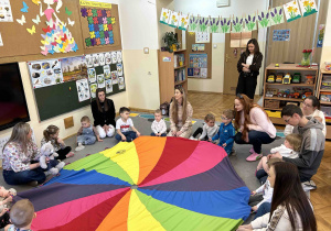 Dzieci wraz z rodzicami bawią się przy chuście animacyjnej.