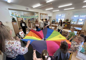 Dzieci wraz z rodzicami bawią się przy chuście animacyjnej.