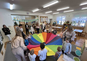 Dzieci wraz z rodzicami bawią się przy chuście animacyjnej.