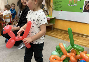 Dziewczynka ma w rękach pieska z balonów.