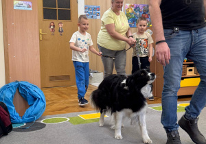 Chłopcy z panią prowadzą psa na smyczy.