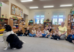 Zadowolone przedszkolaki obserwują aporty psa.