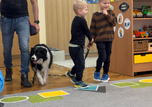 Zadowoleni chłopcy prowadzą psa na smyczy.