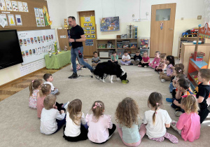 Piesek pije wodę nalaną przez dziewczynkę.