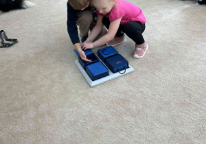 Dzieci z grupy Kropelek chowają suchą karmę do pojemnków.