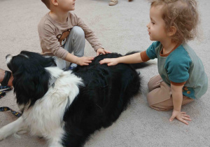 Dzieci głaskają psa.