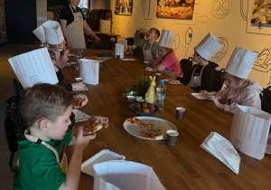 Dzieci zjadają pyszną pizzę.