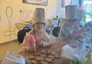 Dziewczynka lukruje ciasteczka.