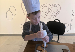 Chłopczyk nakłada lukier na ciasteczka.