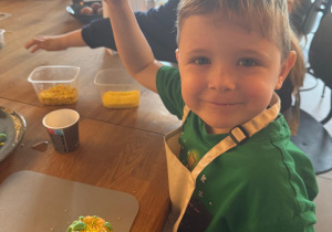 Uśmiechnięty chłopczyk prezentuje swoją babeczkę.