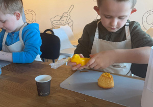 Chłopczyk nakłada lukier na babeczkę.