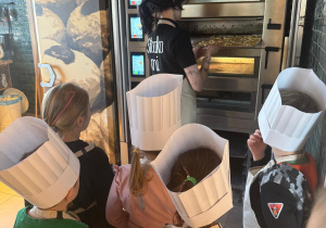 Pani pokazuje dzieciom piec do wypiekania słodkości i bułeczek.