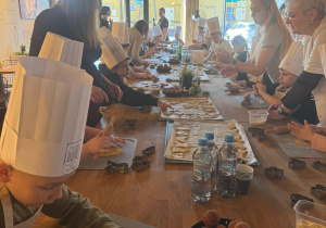 Dzieci za pomocą foremek nadają kształtów ciasteczkom.