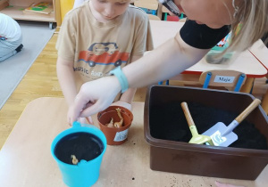 07. Chłopiec wkłada ziarenka roślin do ziemi.