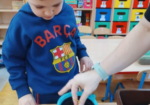 13. Chłopiec wkłada ziarenka roślin do ziemi.