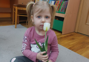 14. Dziewczynka trzyma tulipana w ręce.