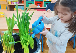 15. Dziewczynka podlewa kwiaty.