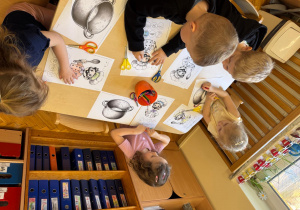 Dzieci siedzą przy stoliku i wykonują kucharza.