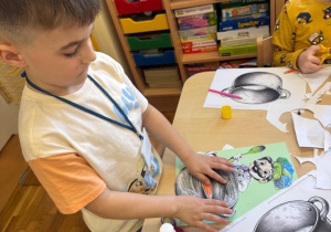 Chłopiec przykleja kucharza i garnek.