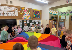 Dzieci tańczą w kole z chustą animacyjną.