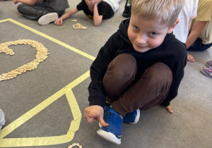 Chłopiec prezentuje ułożoną literę.