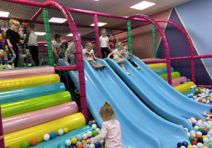 Dzieci zjeżdżają na zjeżdżalni.