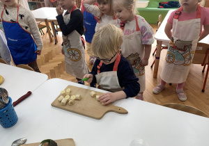 Chłopiec kroi banana na desce.