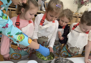 Dziewczynki z panią dietetyk rozcierają awokado.