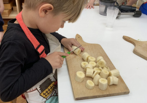 Chłopiec kroi banana.