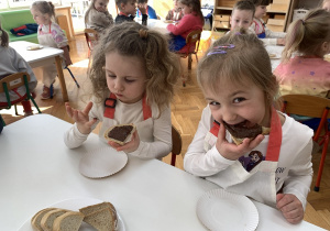 Dziewczynki jedzą chleb z nutellą.