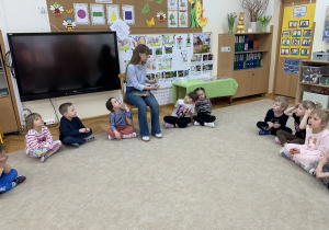 Pani bibliotekarka pokazuje dzieciom ilustracje.