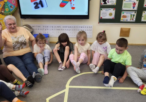 Pięciolatki próbują zdjąć skarpetki bez użycia rąk.