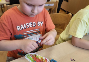 Chłopiec trzyma w ręku kredkę.
