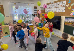 Dzieci tańczą odbijając balony do góry.