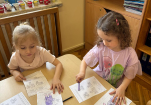 Dziewczynki kolorują kredkami.