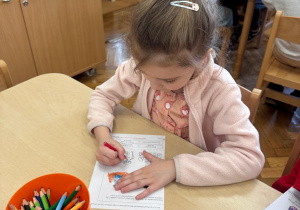 Dziewczynka koloruje ilustracje.