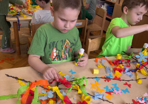 Chłopiec przykleja kolorowe kwiatuszki.