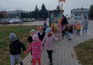 Dziewczynka trzyma motylka na gałązce.