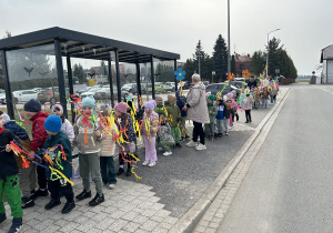 Przedszkolaki trzymają w ręku ozdobione gałązki.