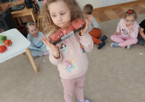 Dziewczynka pokazuje pomidorki malinowe.