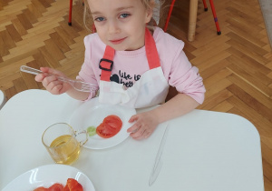 Dziewczynka zajada się pomidorem i ogórkiem.