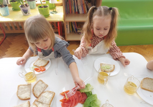 Dziewczynki komponują swoje kanapki z ogórka, pomidora, papryki.