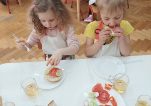 Dziewczynka widelcem nakłada na chleb ulubione warzywa.