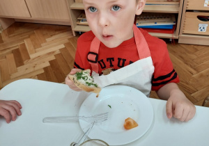 Chłopiec je kanapkę ze szczypiorkiem.