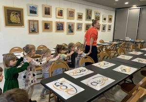 Pani instruktor wprowadza dzieci na salę, gdzie będą odbywać się warsztaty.i