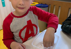 Chłopiec sadzi nasionka rzeżuchy.